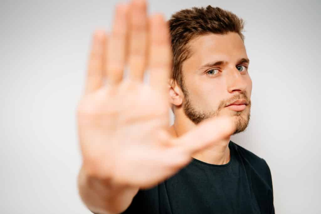 man raisees hand to stop smoking